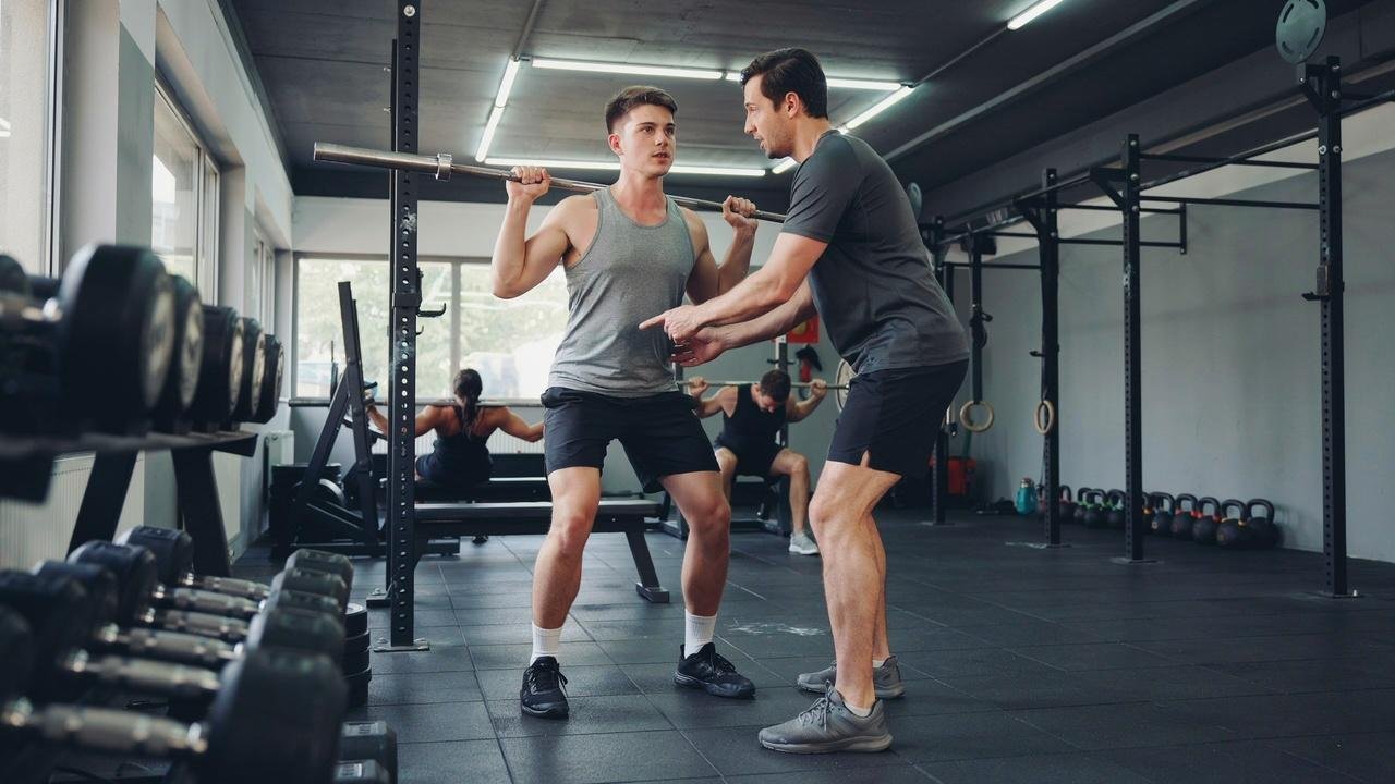 Coach helping a beginner learn proper squat form.