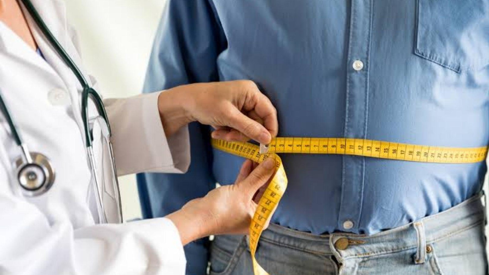doctor measuring patients waist size with a measuring tape.