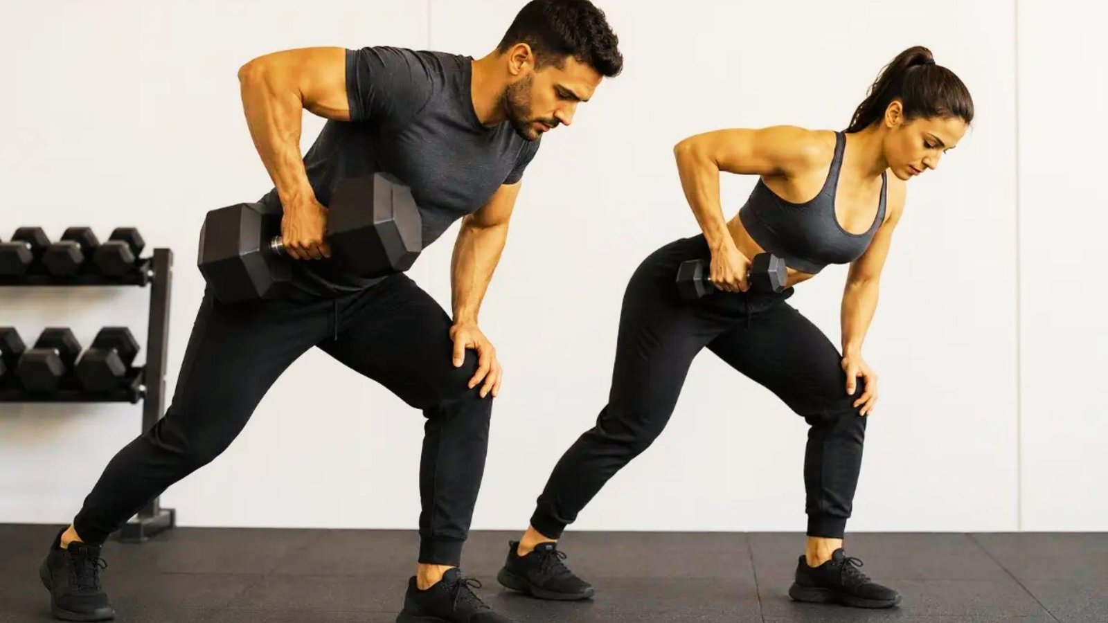 A man and woman performing dumbbell exercises together in a gym setting, focusing on strength training.