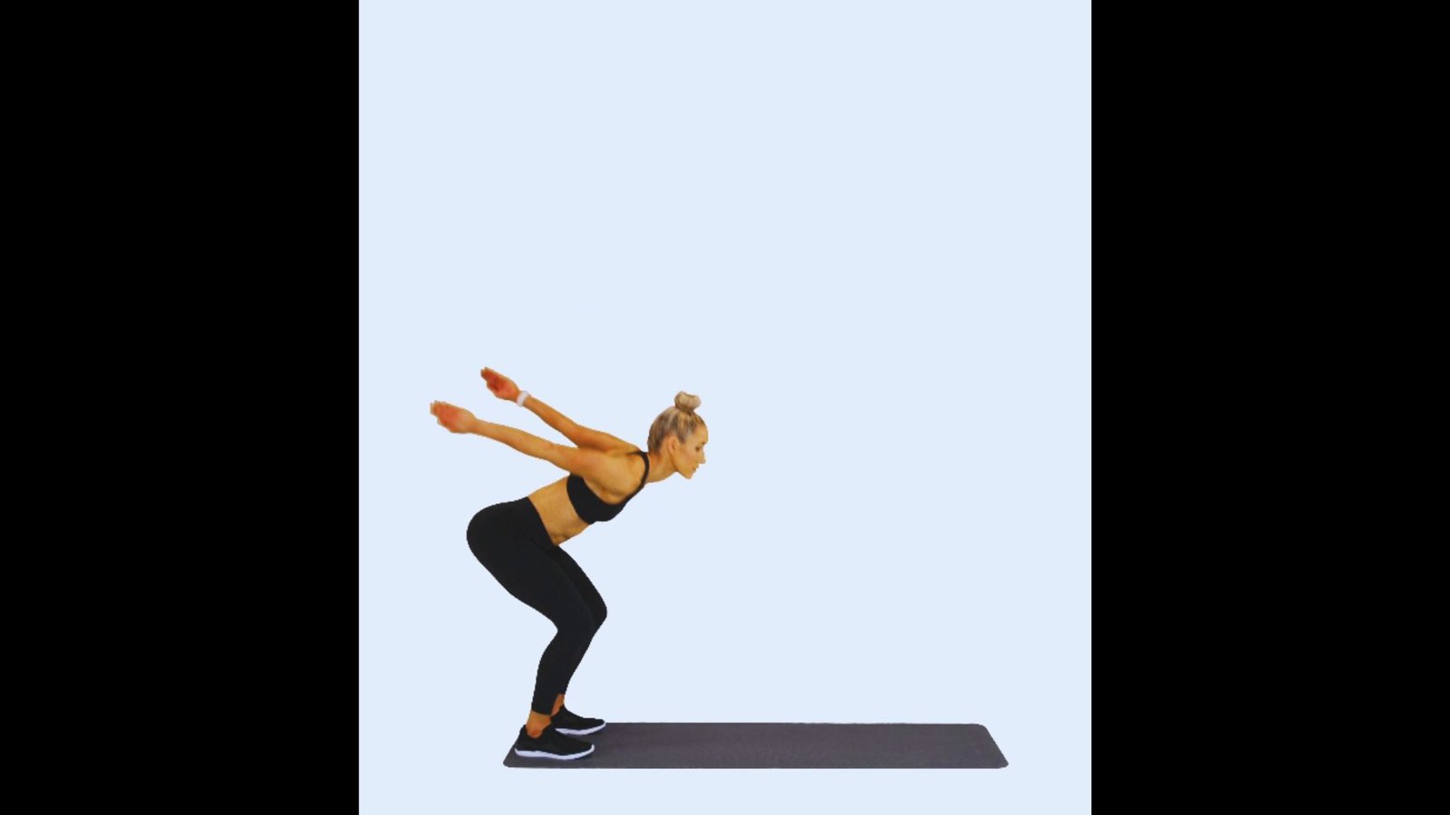 A side-profile shot of an athletic woman mid-leap, performing a broad jump on a gym mat.