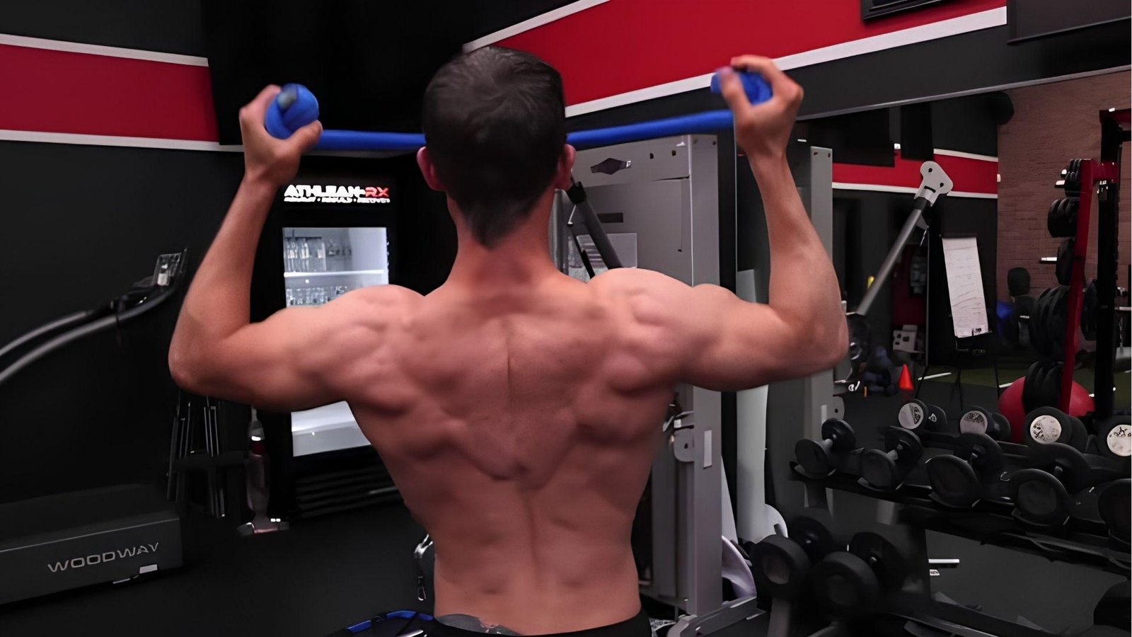 Muscular man performing cable lat pulldown for rear delts in gym