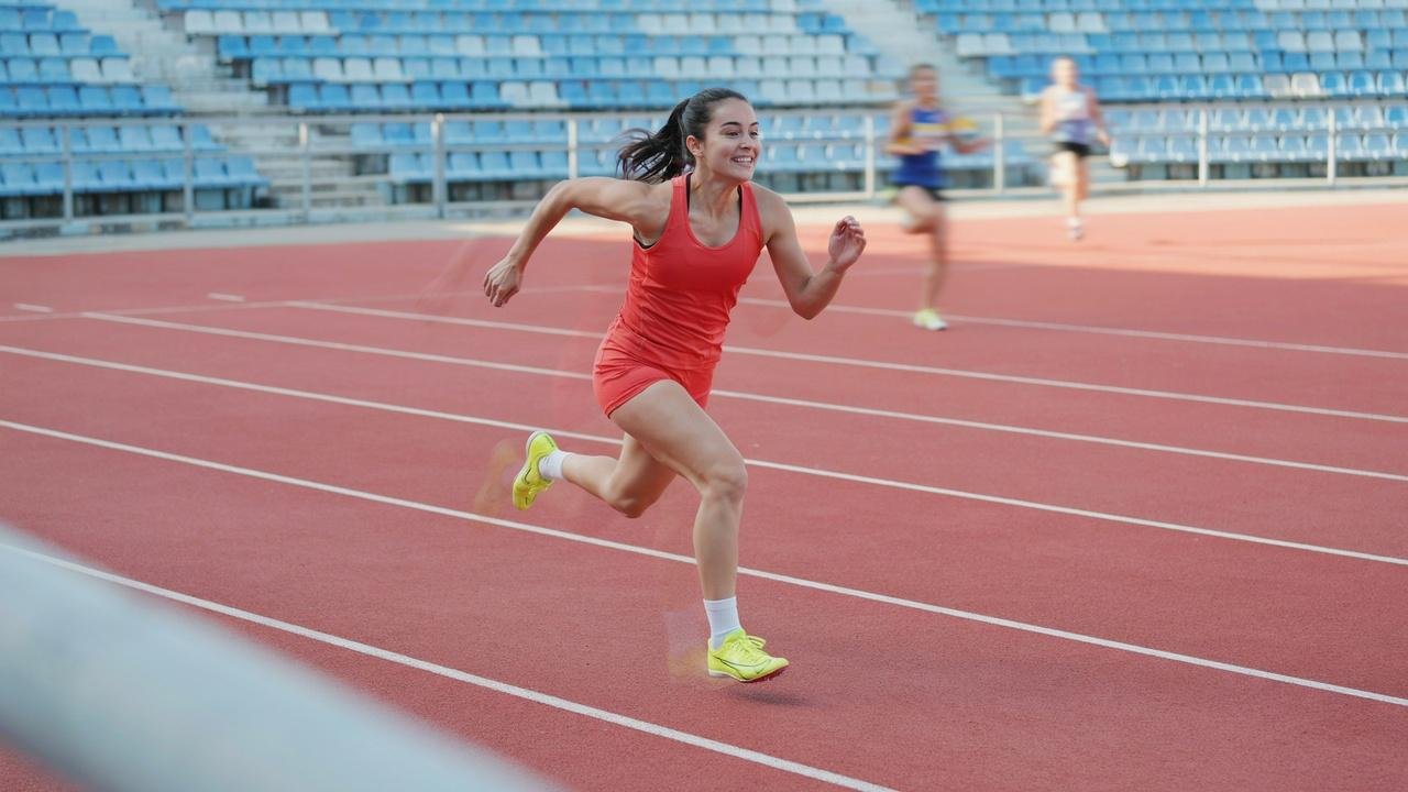 Sprinter running gear sprints on track with runners in background.