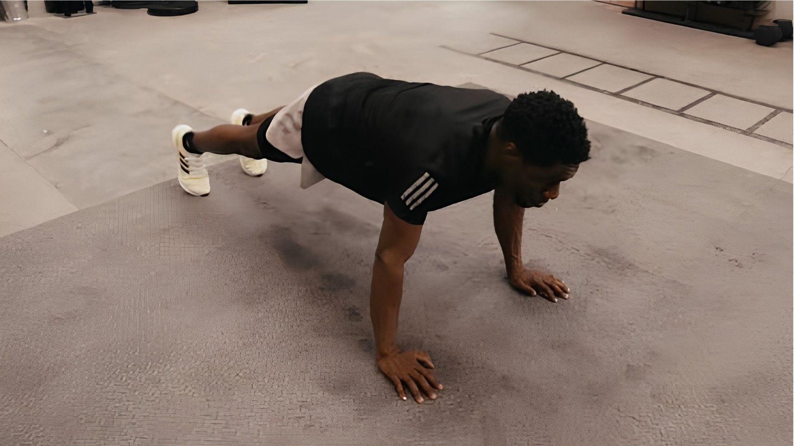 Man in black shirt doing wide-grip push-ups on gym floor