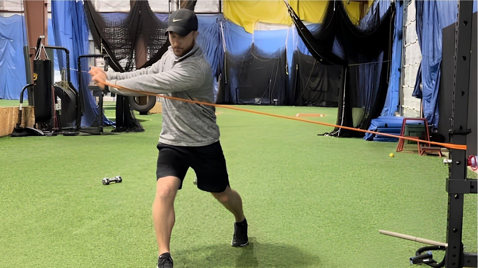 Athlete using resistance bands for baseball swing strength in indoor facility