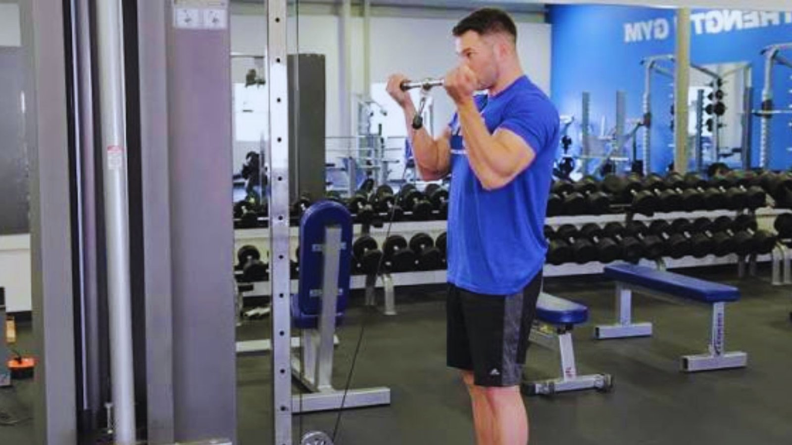 Man performing wide grip cable curls to train short head biceps.