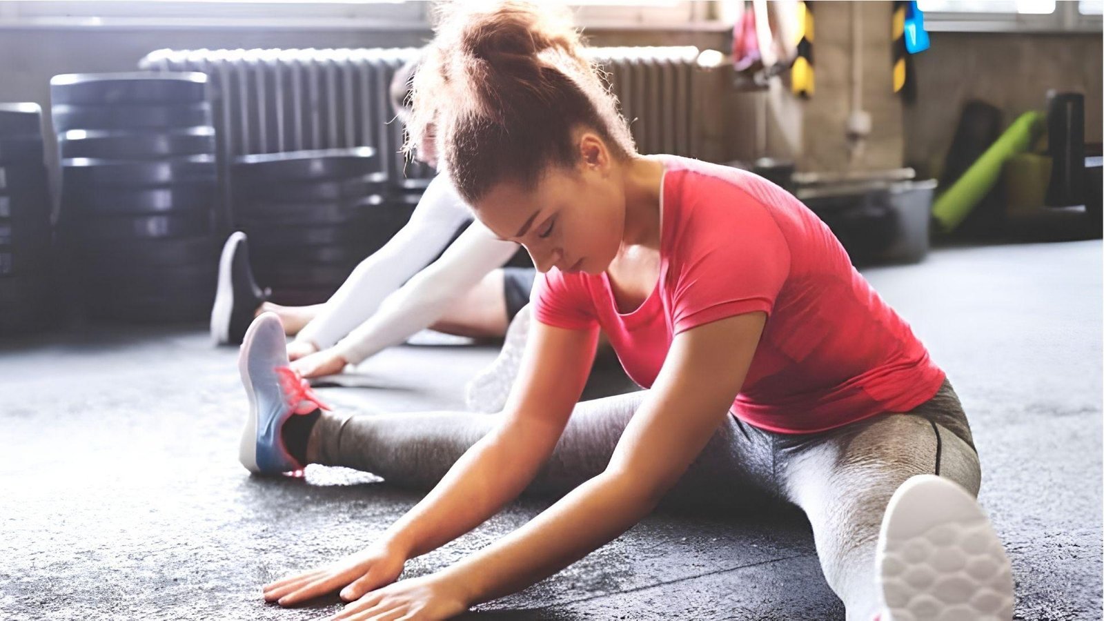 Woman doing seated forward fold stretch in gym for first trimester workout