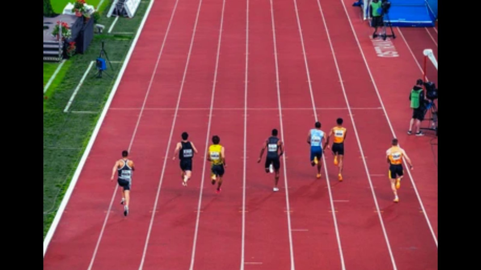 Athletes competing in a mid-distance race on an outdoor running track.